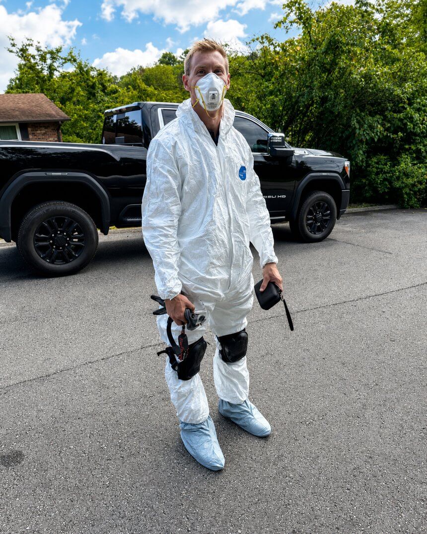 A Magnolia technician in a protective coverall and respirator before entering a crawlspace