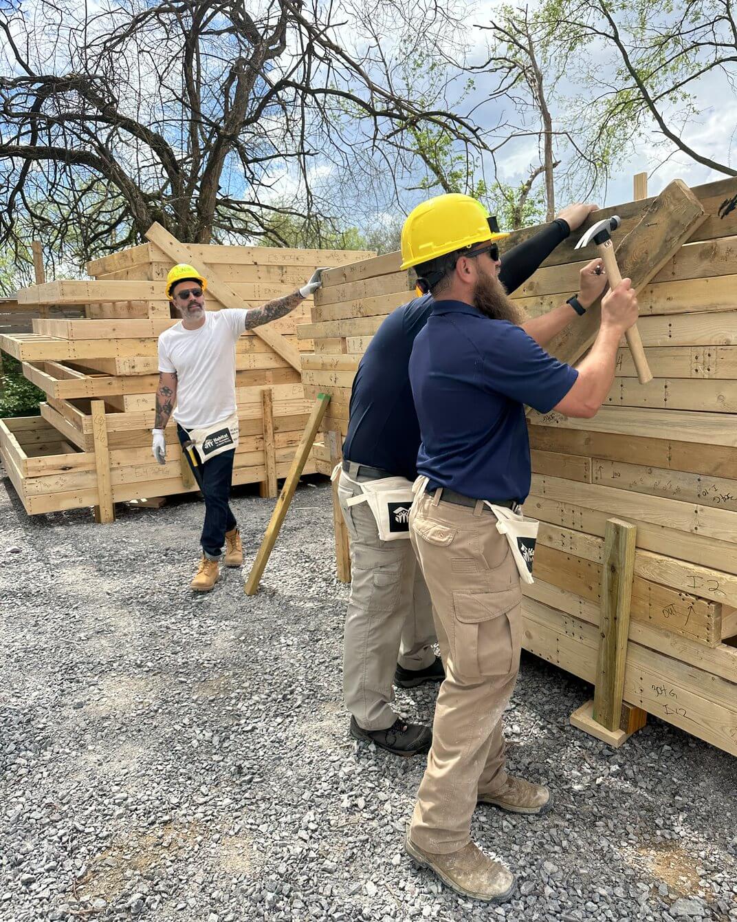 A Magnolia team member in a hard hat framing a wall on a community build site